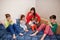 Happy big family is having fun together in bedroom. Large family morning concept. Mother with four kids wear pajamas drink tea in