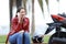 Happy biker calling insurance beside her motorbike