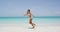 Happy bikini woman jumping of joy and success on perfect white sand beach
