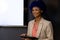 Happy biracial casual businesswoman with blue afro making presentation at whiteboard with copy space