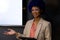 Happy biracial casual businesswoman with blue afro making presentation at whiteboard with copy space