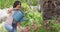 Happy biracial woman gardening, watering plants with watering can