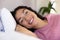 Happy biracial woman lying in bed at sunny home
