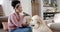 Happy biracial woman petting dog and talking on smartphone at home, slow motion