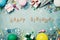 Happy birthday banner. Colorful holiday supplies on blue vintage table top view. Flat lay style.