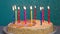 Happy birthday cake with burning colorful candles on blue background