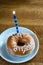 Happy birthday donut with candle on white dessert plate on wooden table