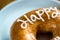 Happy birthday donut on white dessert plate on wooden table. closeup