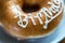 Happy birthday donut on white dessert plate on wooden table. closeup