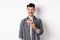 Happy birthday guy making wish on b-day cake, smiling and looking at lit candle excited, standing on white background