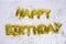 Happy birthday lettering of frustrated gold balloons isolated with colorful confetti on white background. Congratulations