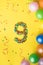 Happy Birthday number 9 made of candies with colorful balloons on yellow background
