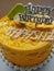 Happy Birthday tagged yellow orange mango flavour birthday cake display