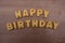 Happy Birthday text composed with biscuit letters over a wooden board