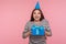 Happy birthday to me! Joyful optimistic woman with party cone hat smiling at camera and holding wrapped gift box