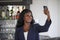 Happy black afro american woman in casual elegant clothes taking selfie portrait photo with mobile phone