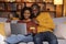 Happy black couple banking from home, using laptop, credit card