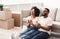 Happy Black Couple Celebrating Moving Apartment Sitting Among Boxes Indoors