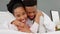 Happy black couple having fun in bed, hug and bonding in a bedroom. Portrait of a caring husband and wife being playful