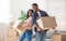 Happy black couple holding carton boxes and looking at each other in their new apartment, panorama