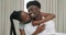 Happy black couple, hug and relax for love, affection or embrace together on bed at home. African woman hugging man with