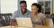 Happy black couple laughing and watching video on laptop