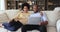 Happy Black couple rest on cozy couch talk use laptop