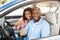 Happy black couple sitting in car gesturing thumbs up