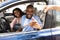 Happy black couple sitting in new car taking keys