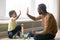 Happy black dad and toddler son giving high-five playing together