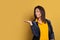 Happy black girl with empty open hand for advertising marketing or product placement posing on colorful yellow background