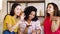 Happy black girl showing engagement ring to multiracial female friends at home