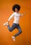 Happy black guy jumping on orange studio background