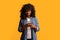 Happy black lady using modern smartphone on yellow