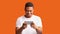 Happy black man using smartphone over orange background