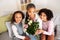 Happy Black Mother Holding Flowers Receiving Greetings From Daughters Indoor