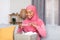 Happy black muslim lady unpacking parcel, making photo of her new shoes on smartphone for positive online store feedback
