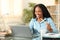 Happy black tele worker eating snack at home