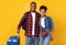 Happy Black Travelers With Suitcase Standing Over Yellow Background