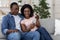 Happy black wife showing her husband photos on smartphone