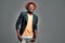 Happy black young man wears dark Jacket and yellow t-shirt posing with pleased smile