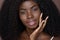 Happy black young woman touching flawless face skin on brown background.