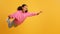 Happy black youngster girl flying in mid air, yellow background