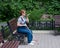 Happy blind pregnant woman sitting on bench and talking on smartphone.