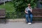 Happy blind pregnant woman sitting on bench and talking on smartphone.