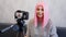 Happy blogger in pink wig in front of the camera on a tripod