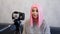 Happy blogger in pink wig in front of the camera on a tripod