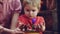 Happy blond boy helps to plant seedlings at parents home. Plant flowers. Spring flowers at home. Baby in red. Family day