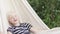 Happy blond boy lies in a hammock