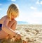 Happy blond girl in swimwear on beach playing